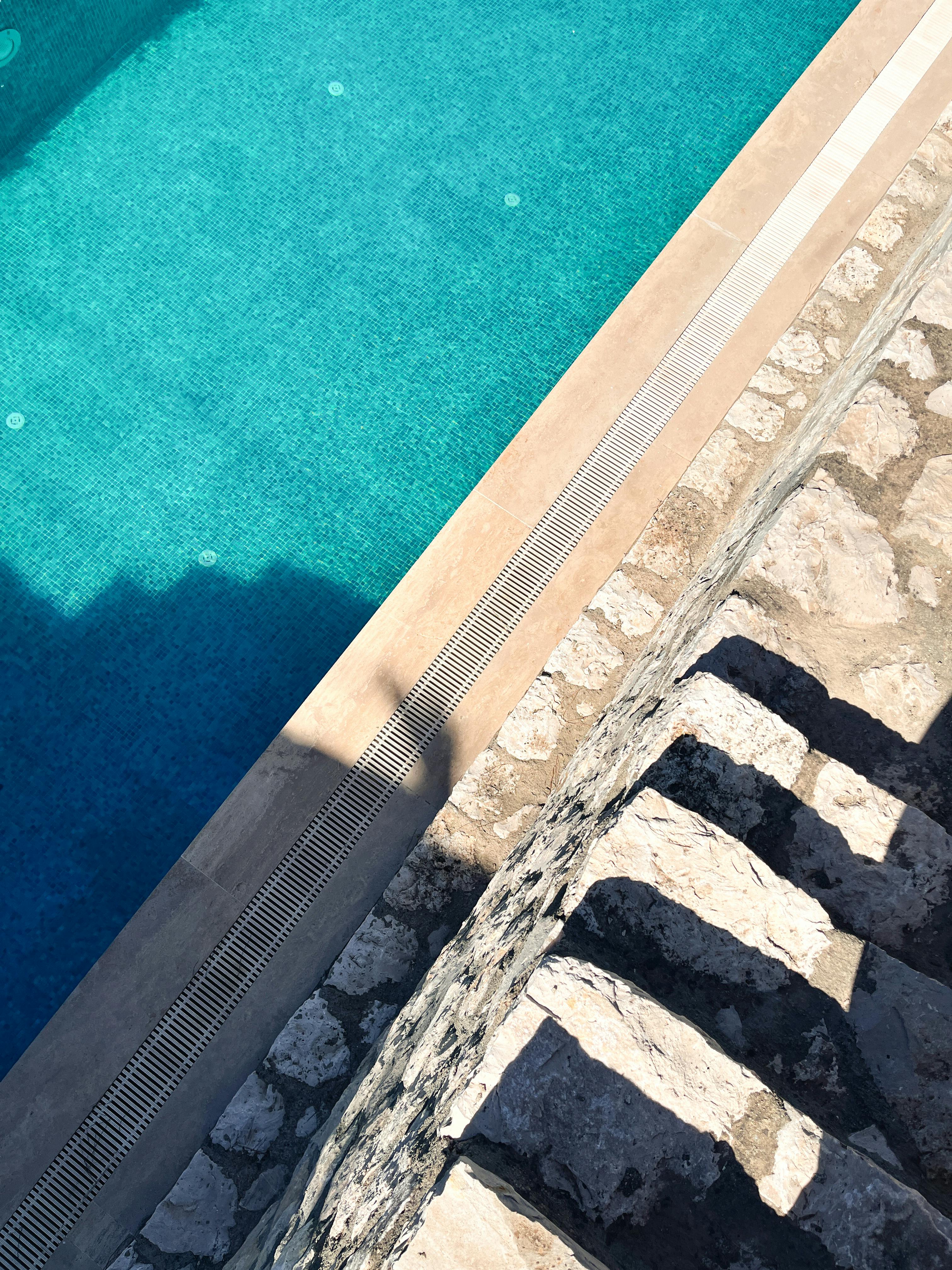 Free Sunlit stone steps lead to a turquoise pool, casting soft shadows in İzmir. Stock Photo