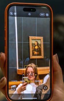 A smartphone capturing the Mona Lisa in the Louvre Museum, Paris.