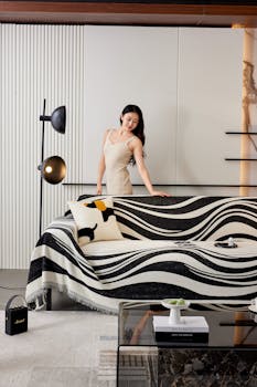A woman arranges a stylish black and white throw in a modern living room.