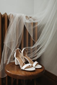 Elegant white bridal shoes with veil on a rustic wooden stool. Perfect for wedding theme images.