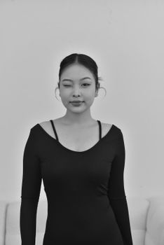 Monochrome portrait of a young woman in a black dress with a confident expression.