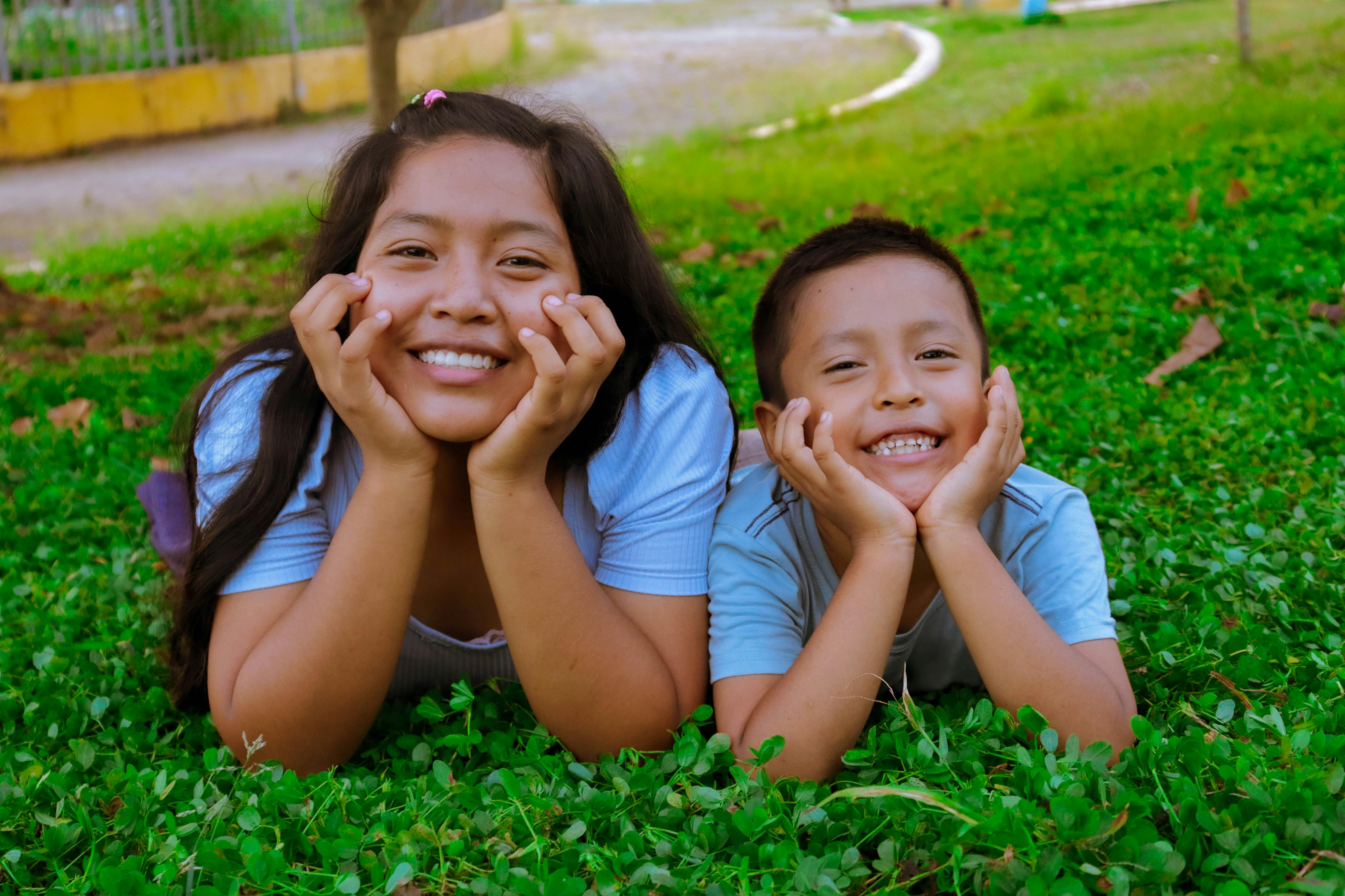 two children laying on the grass smiling