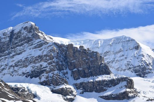 Breathtaking view of snow-covered Rocky Mountains under a vibrant blue sky in Alberta, Canada.