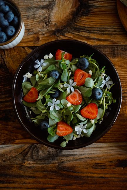 A vibrant bowl of fresh fruit salad featuring strawberries and blueberries in a rustic setting.