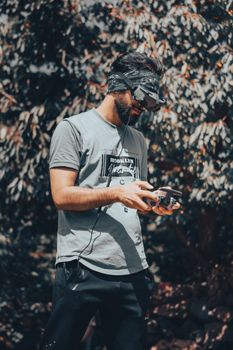 Young man using VR goggles and controlling a drone outdoors.