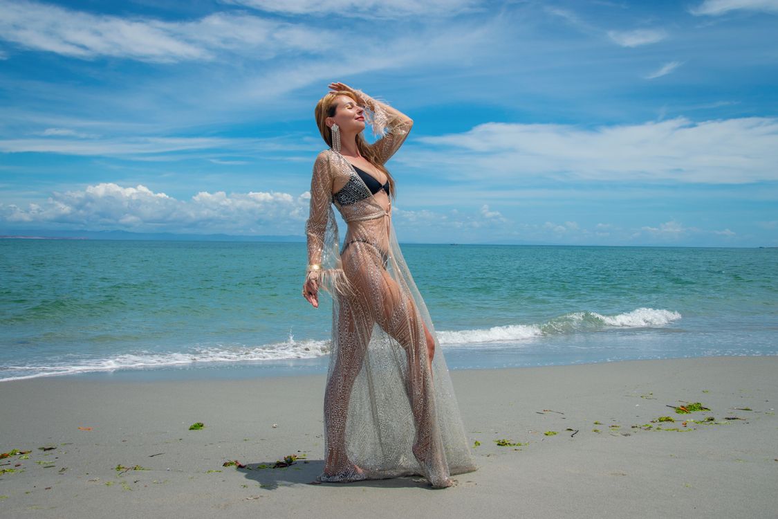 A woman in a long dress standing on the beach · Free Stock Photo