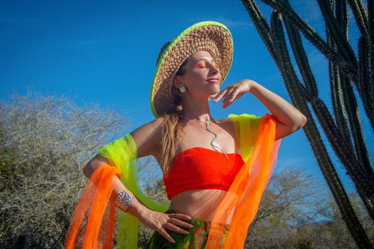 A woman in vibrant attire enjoying the sunny outdoors with a cactus backdrop.