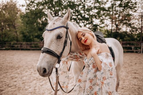 Free A woman in a floral dress embraces a white horse in a rural outdoor setting. Stock Photo