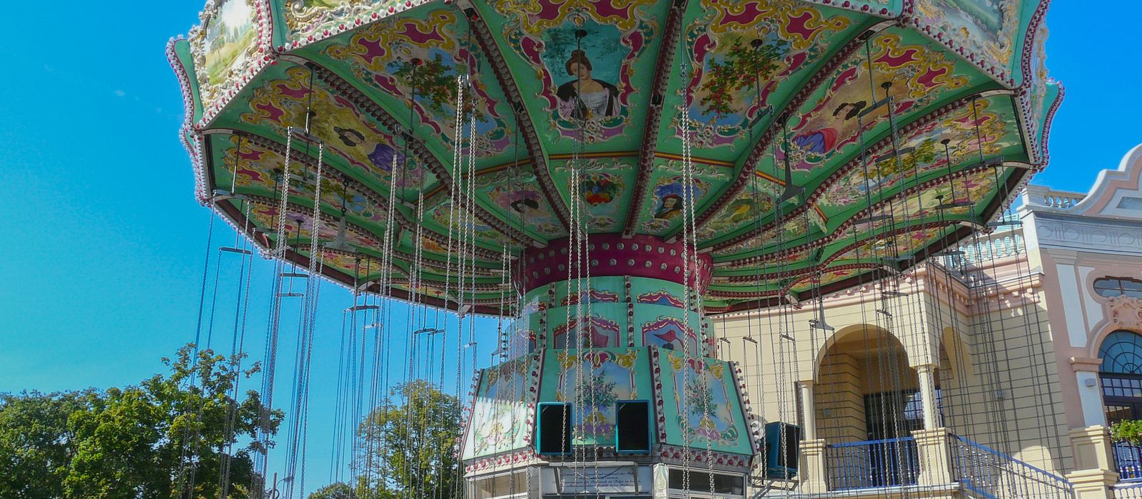 Colorful vintage carousel in a sunny amusement park with ornate design.