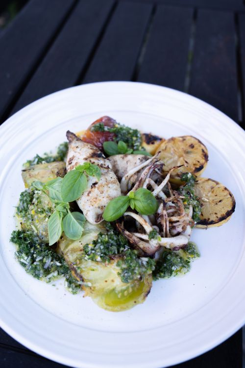 Free A gourmet dish featuring grilled octopus and seafood garnished with fresh herbs and vegetables. Stock Photo