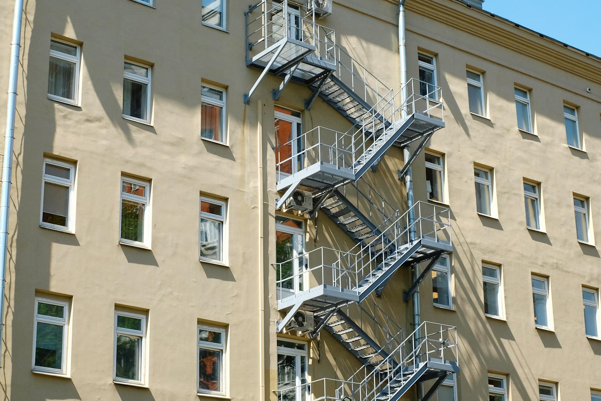 Side view of a classic Moscow apartment building with fire escape and multiple windows.