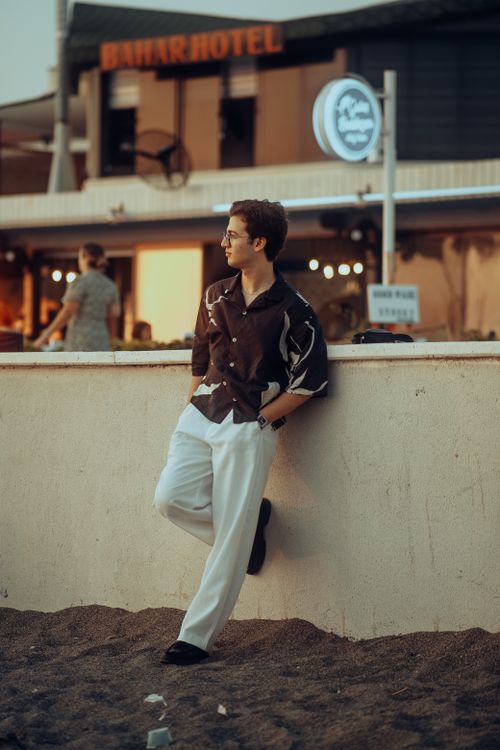 Free Fashionable man in casual attire stands by a wall with urban background. Stock Photo