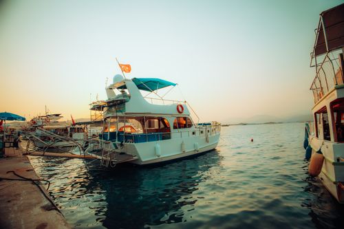 Free Explore a peaceful harbor scene with anchored boats during a stunning sunset. Stock Photo