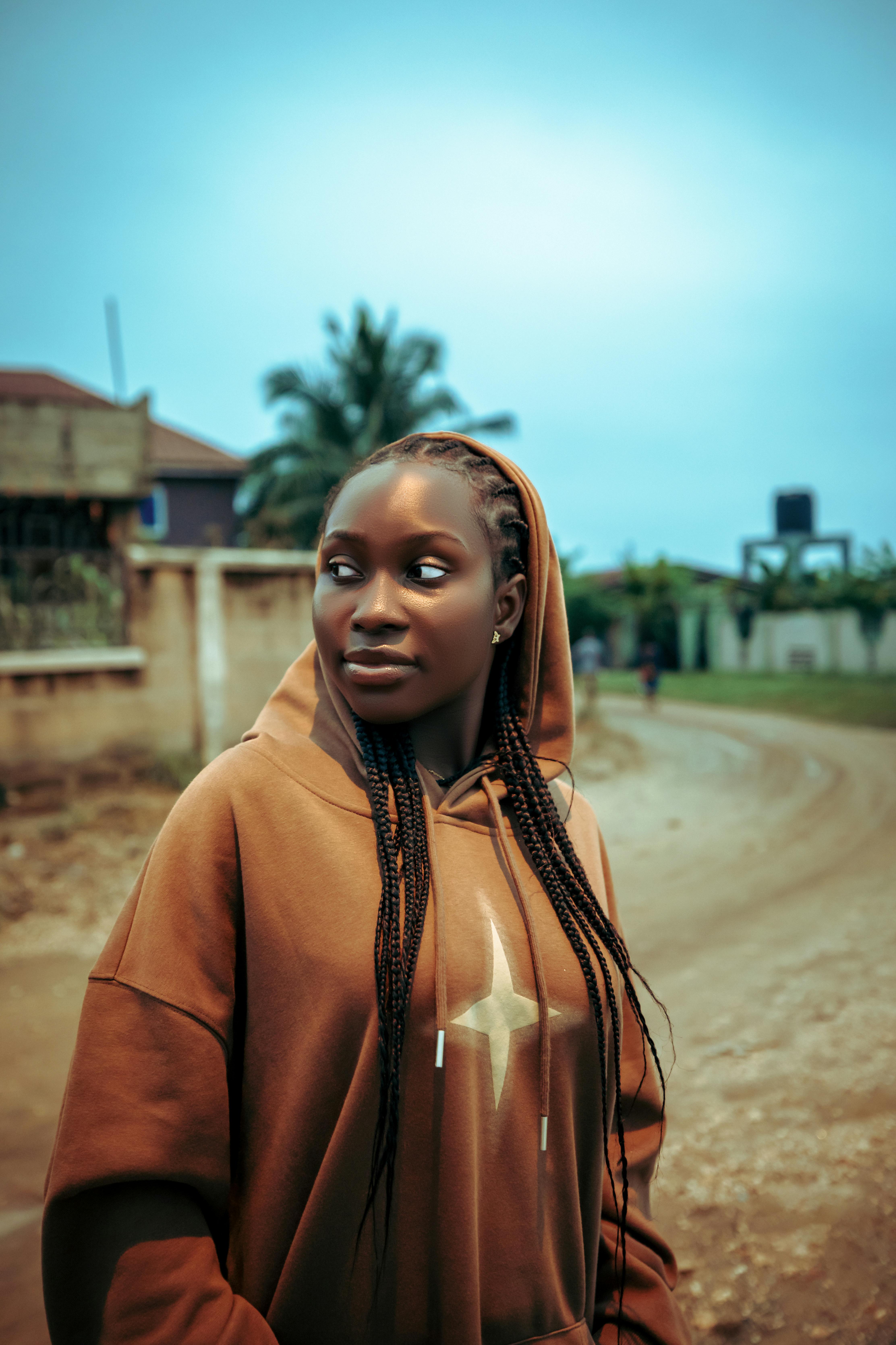Young woman in a brown hoodie outdoors, exuding a cool and casual vibe.