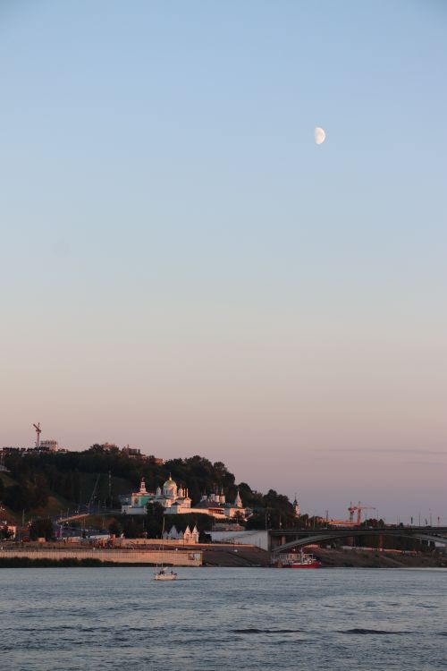 Free Beautiful riverside cityscape with a bridge and crescent moon at dusk. Stock Photo