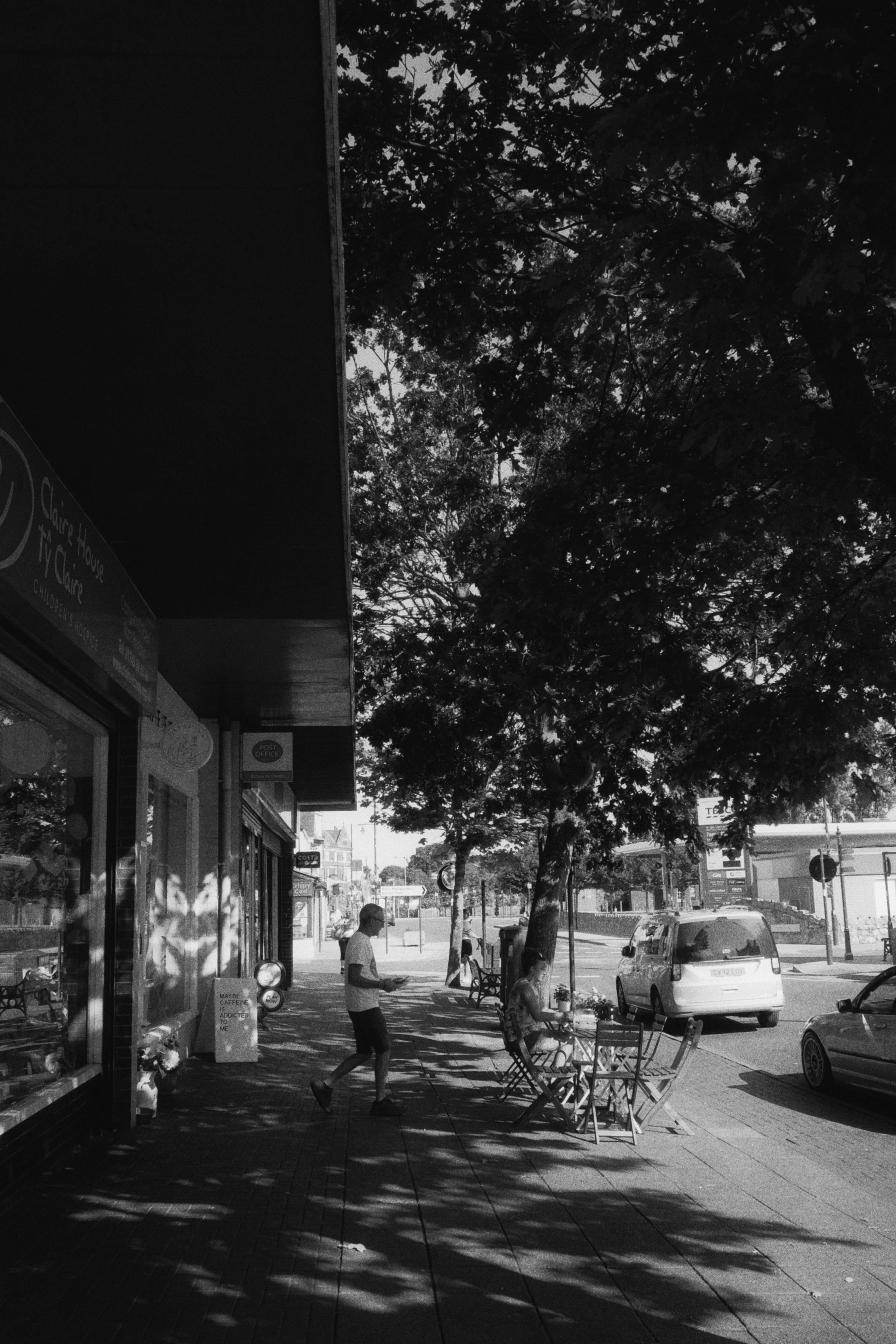 Black and white photo of a lively city street with people and cars.