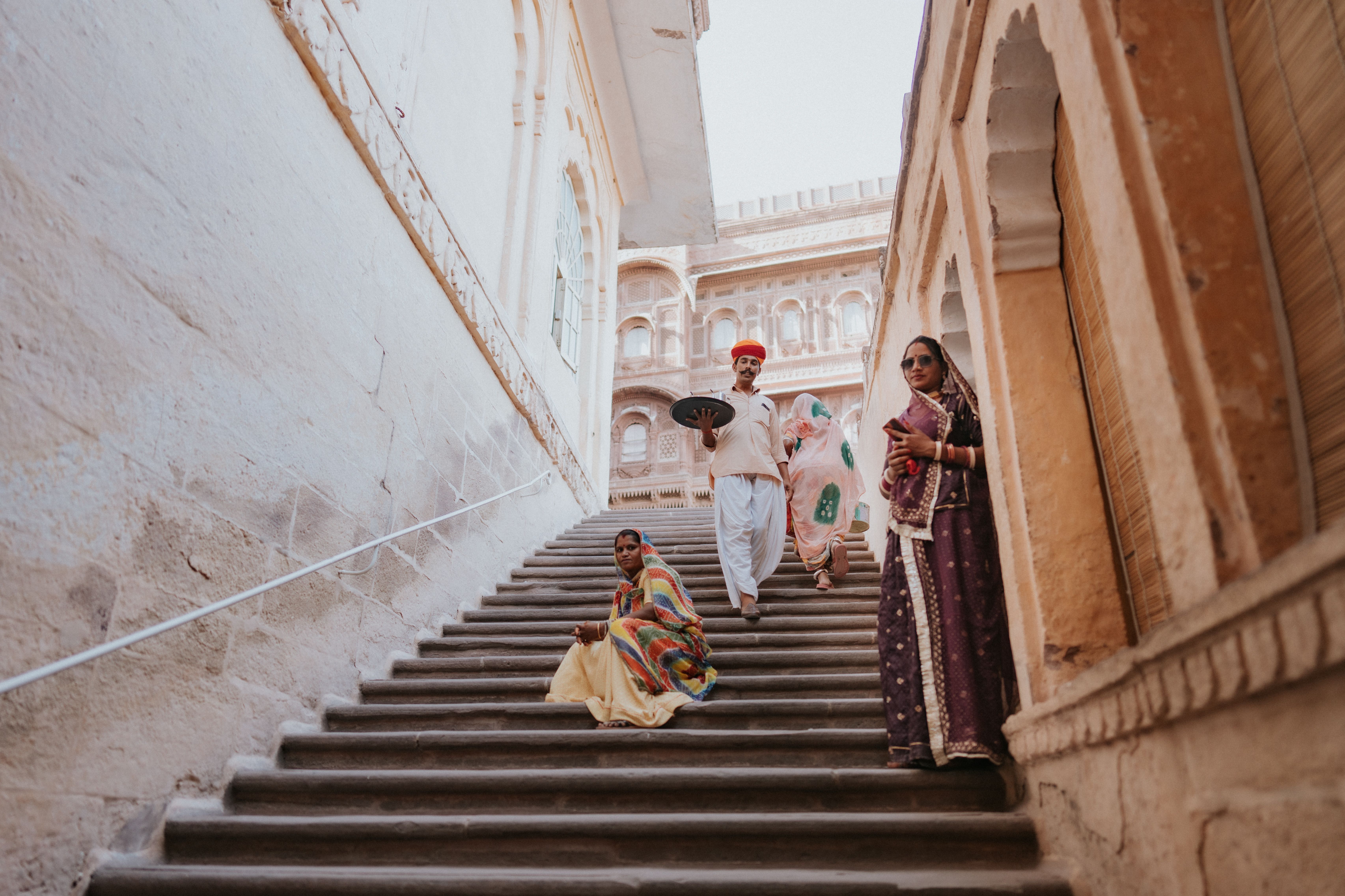 People in vibrant attire on steps of a historic building in Udaipur, India.