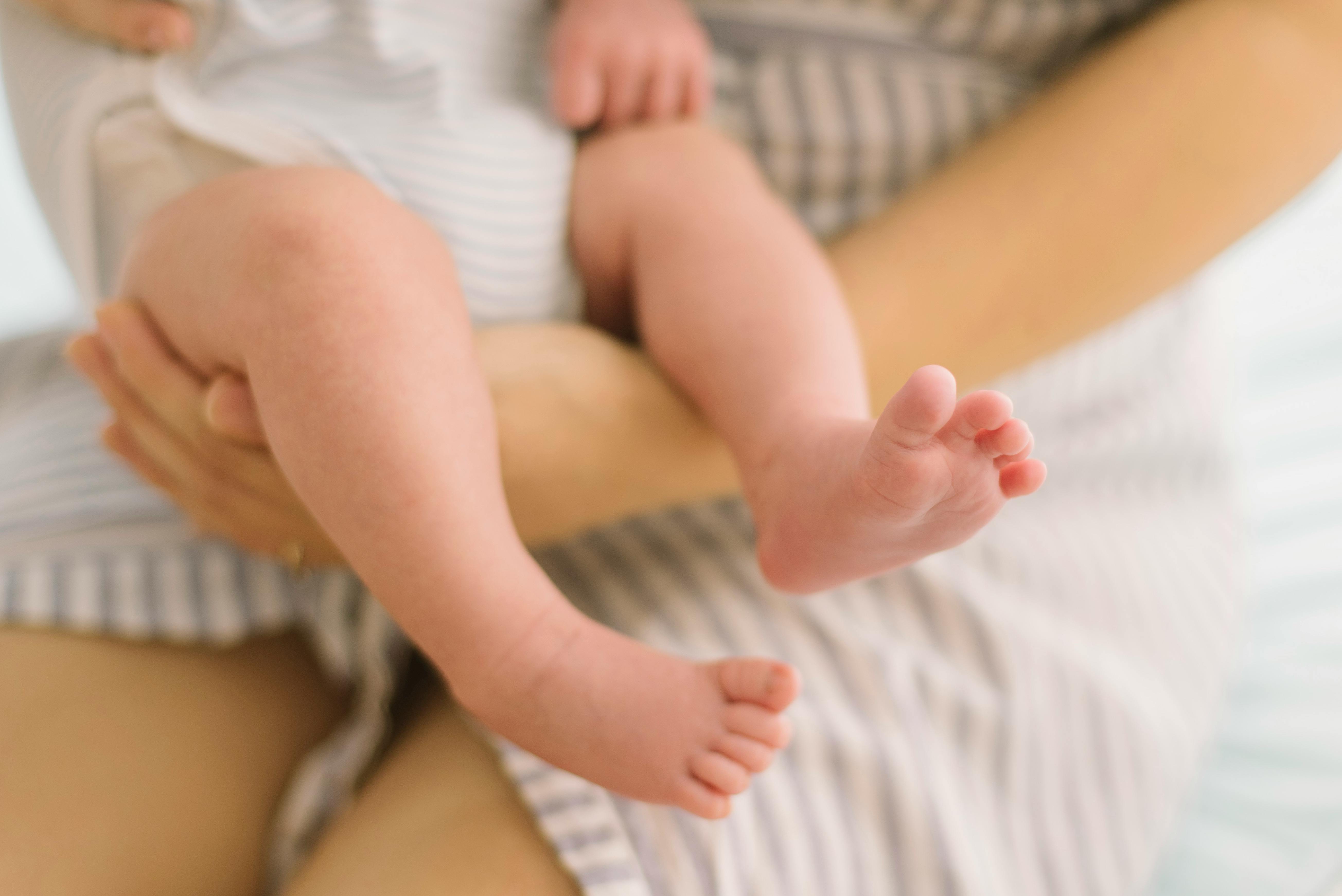 a woman holding a baby s feet with a blanket