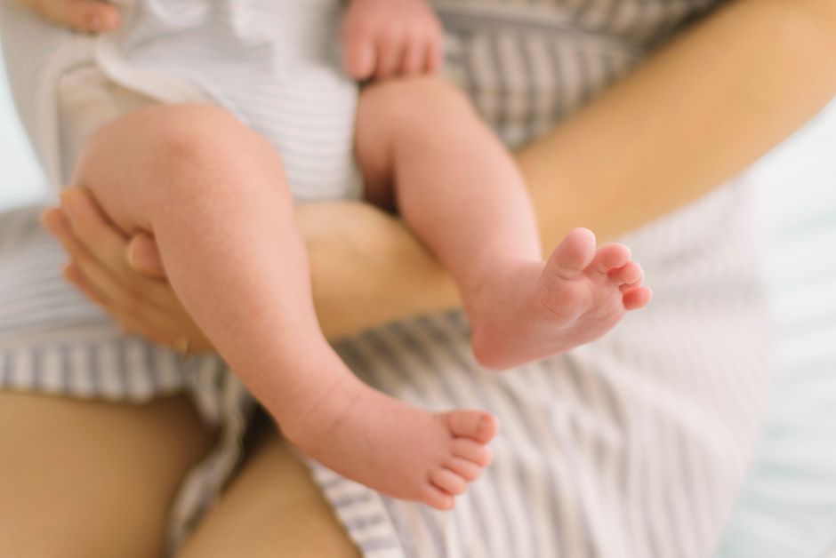 A tender moment of a mother gently holding her baby's feet, showcasing love and care.