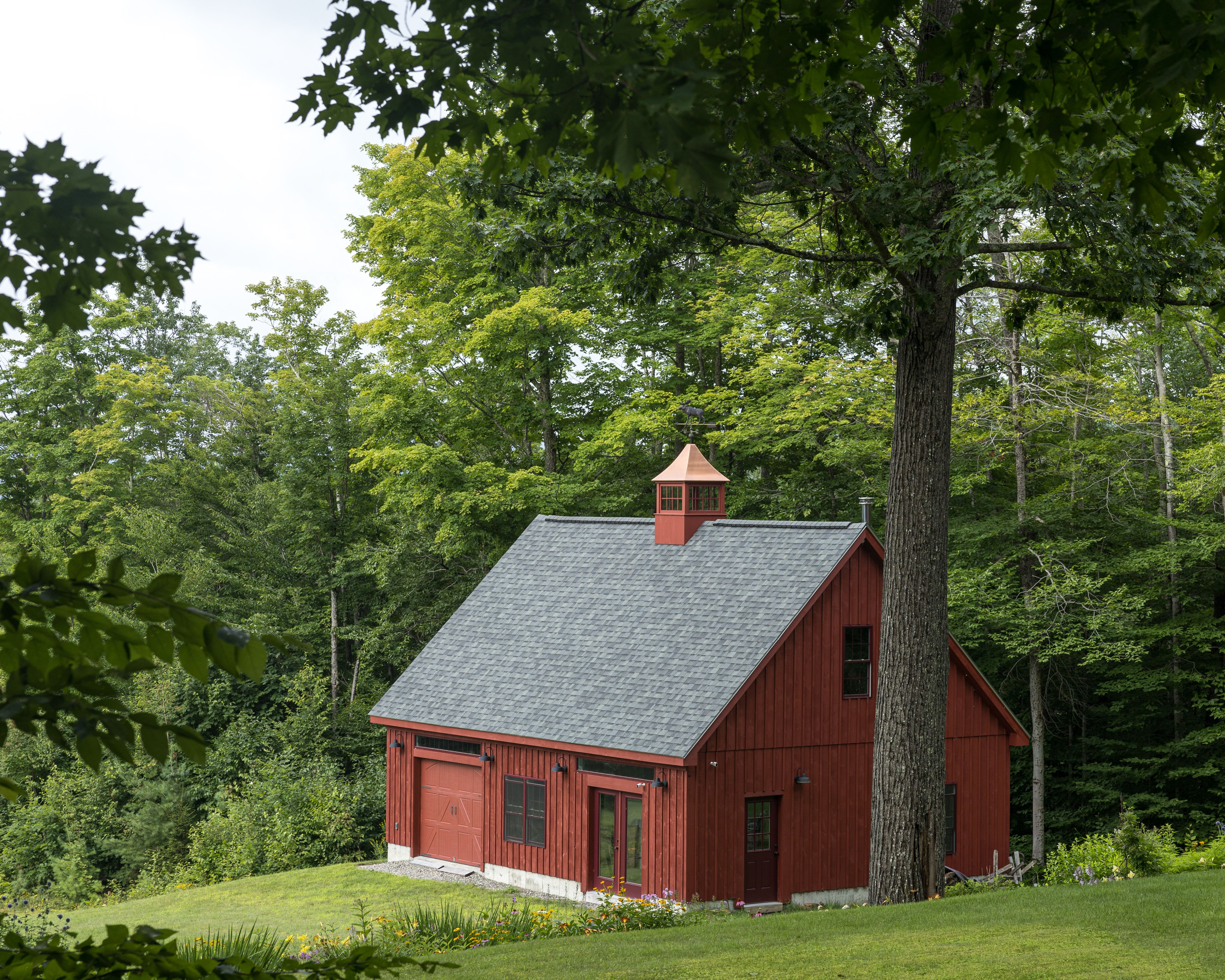 A red barn sits in the middle of a lush green field · Free Stock Photo