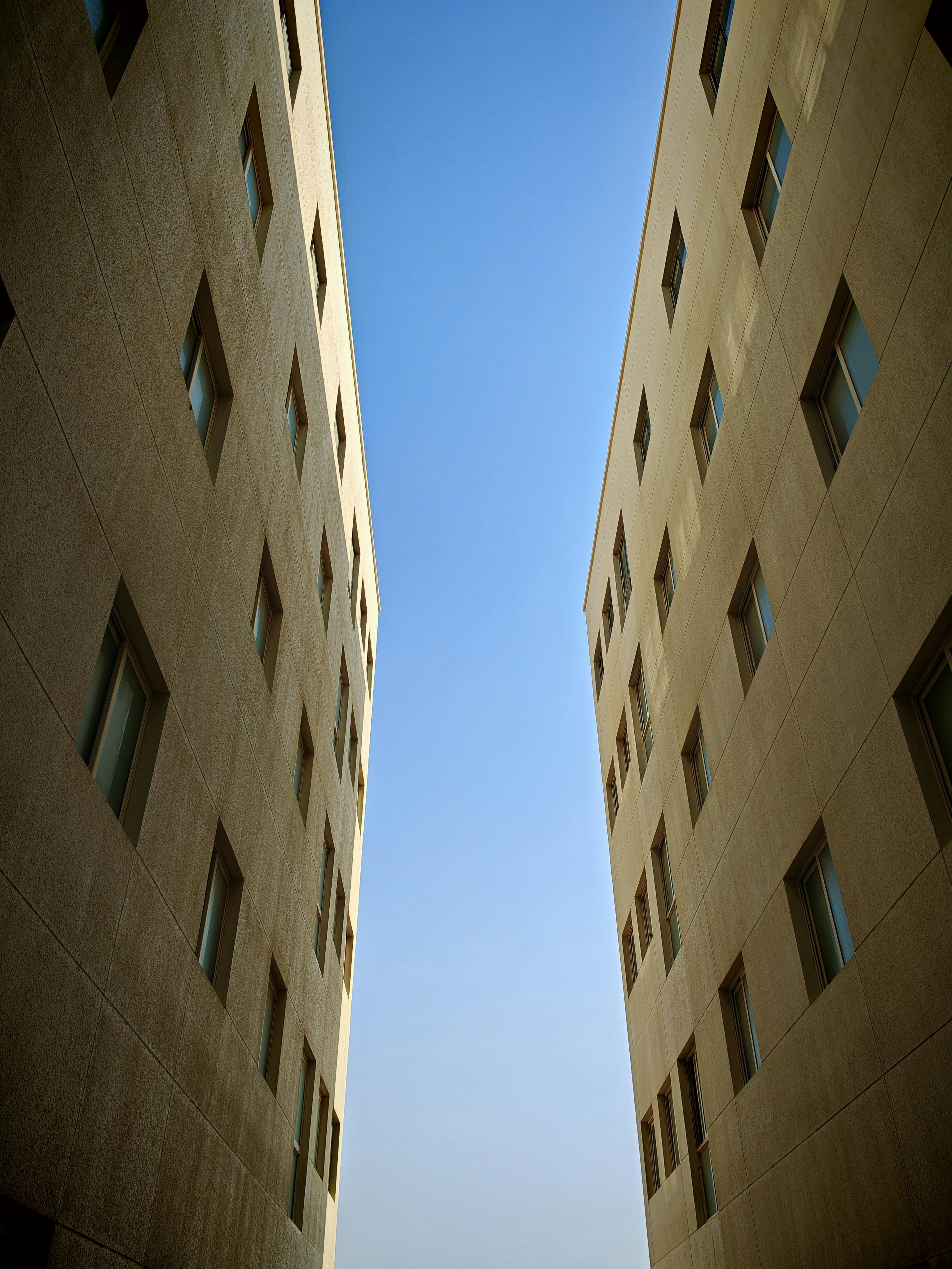 Symmetrical view of two modern buildings with clear blue sky in the backdrop.