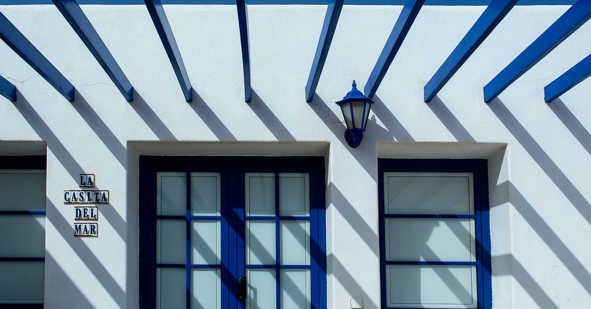 Contemporary building facade with blue doors and shadows in Lanzarote, Spain.