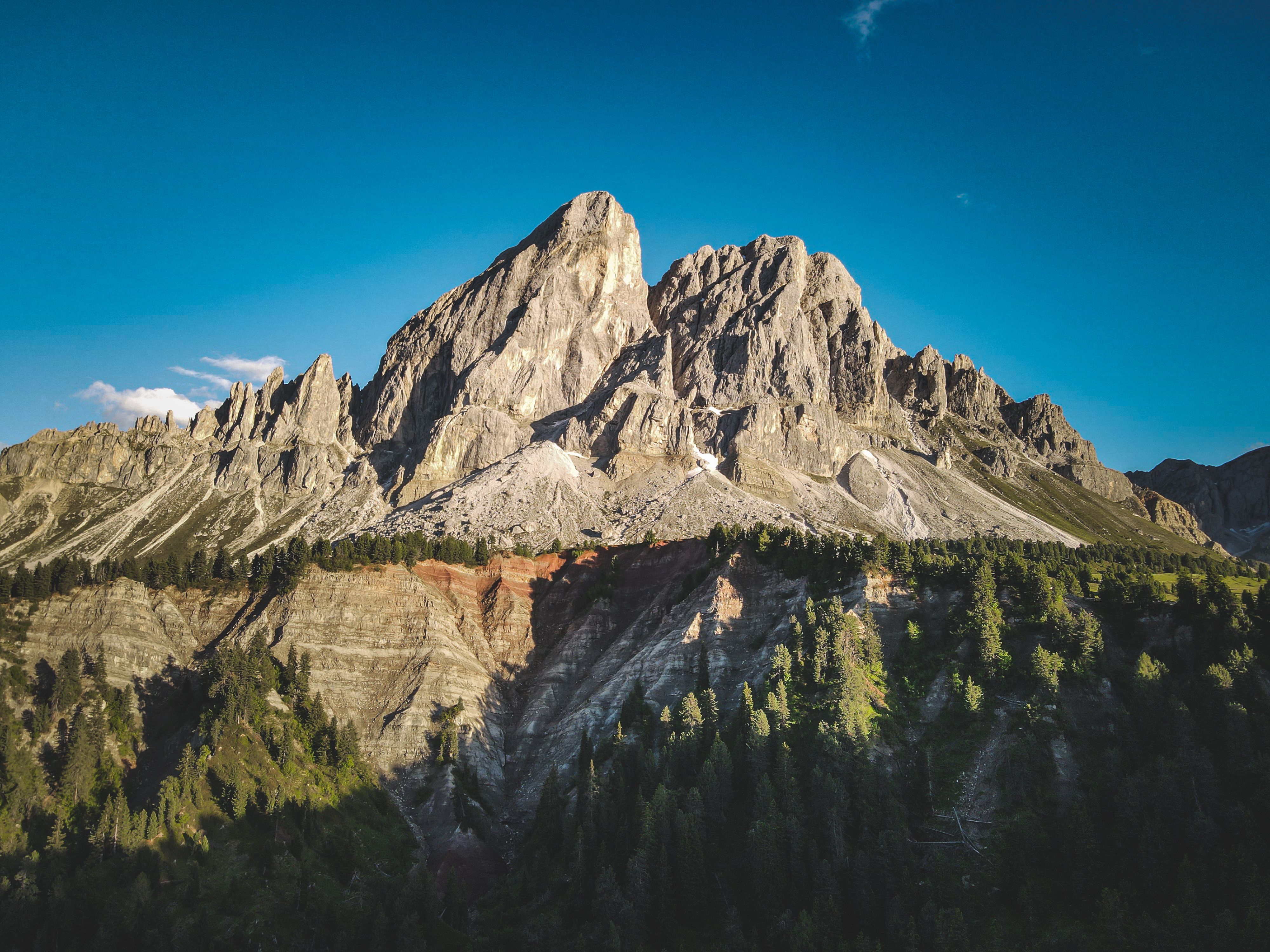 A mountain with a blue sky and green trees · Free Stock Photo