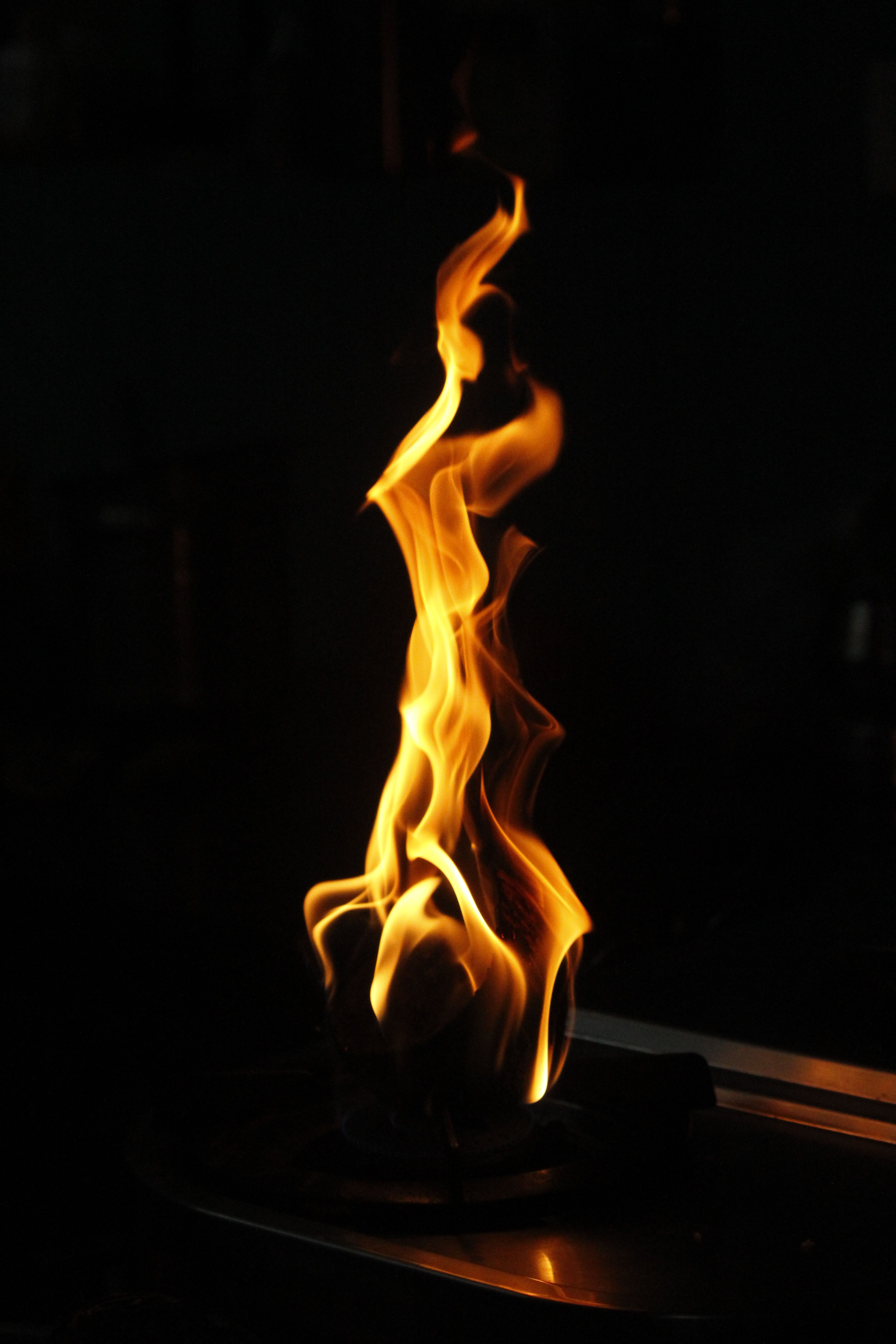 A captivating image of a single flame rising against a dark backdrop, emphasizing its bright and warm glow.