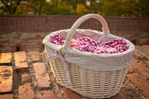 White wicker basket with striped liner and red gingham cloth on bricks