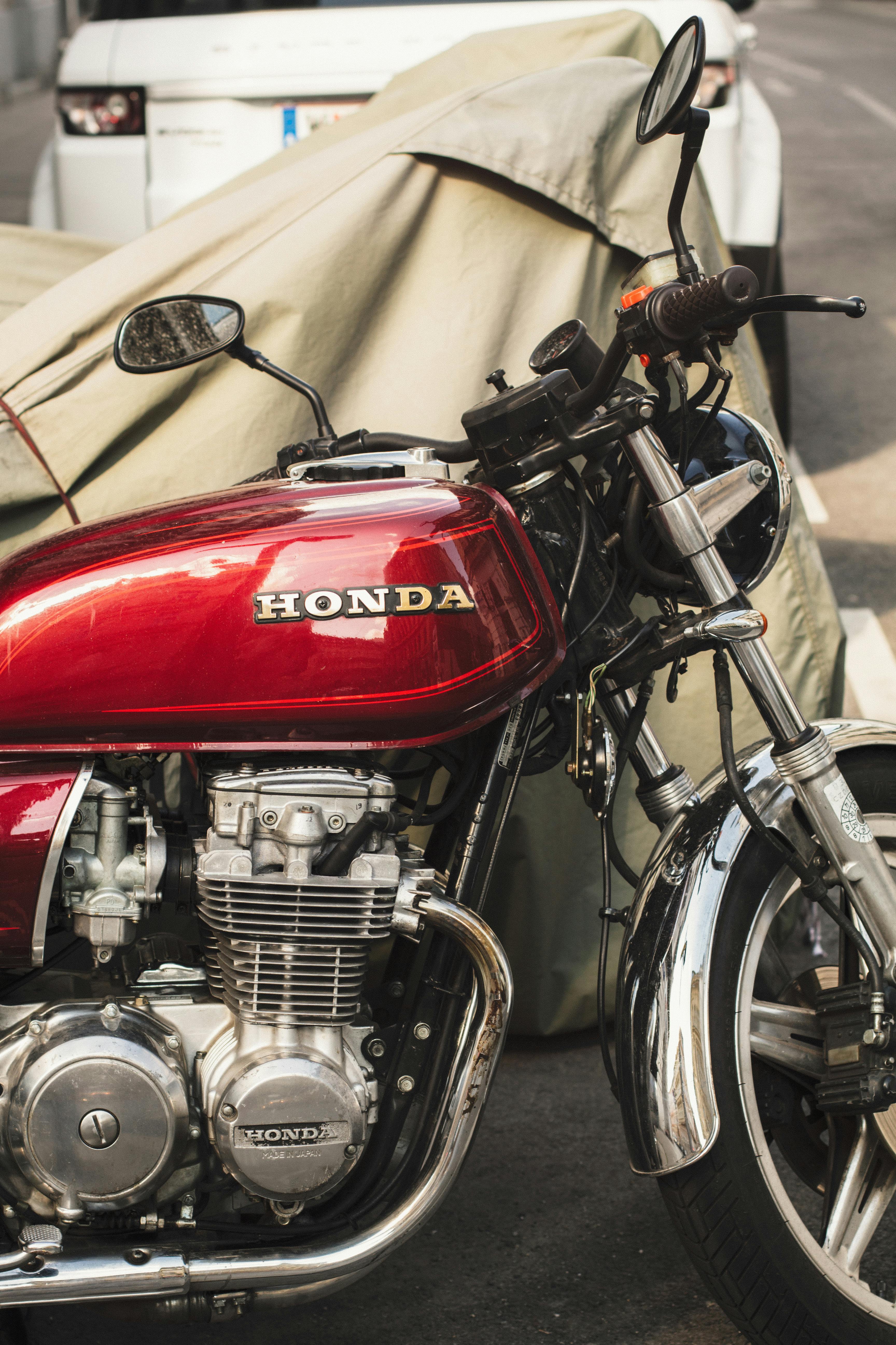 Vintage Honda motorcycle parked with chrome details under a cover outdoors.