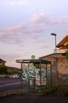 A quaint bus stop with graffiti art under the warm glow of a sunset, showcasing urban charm.