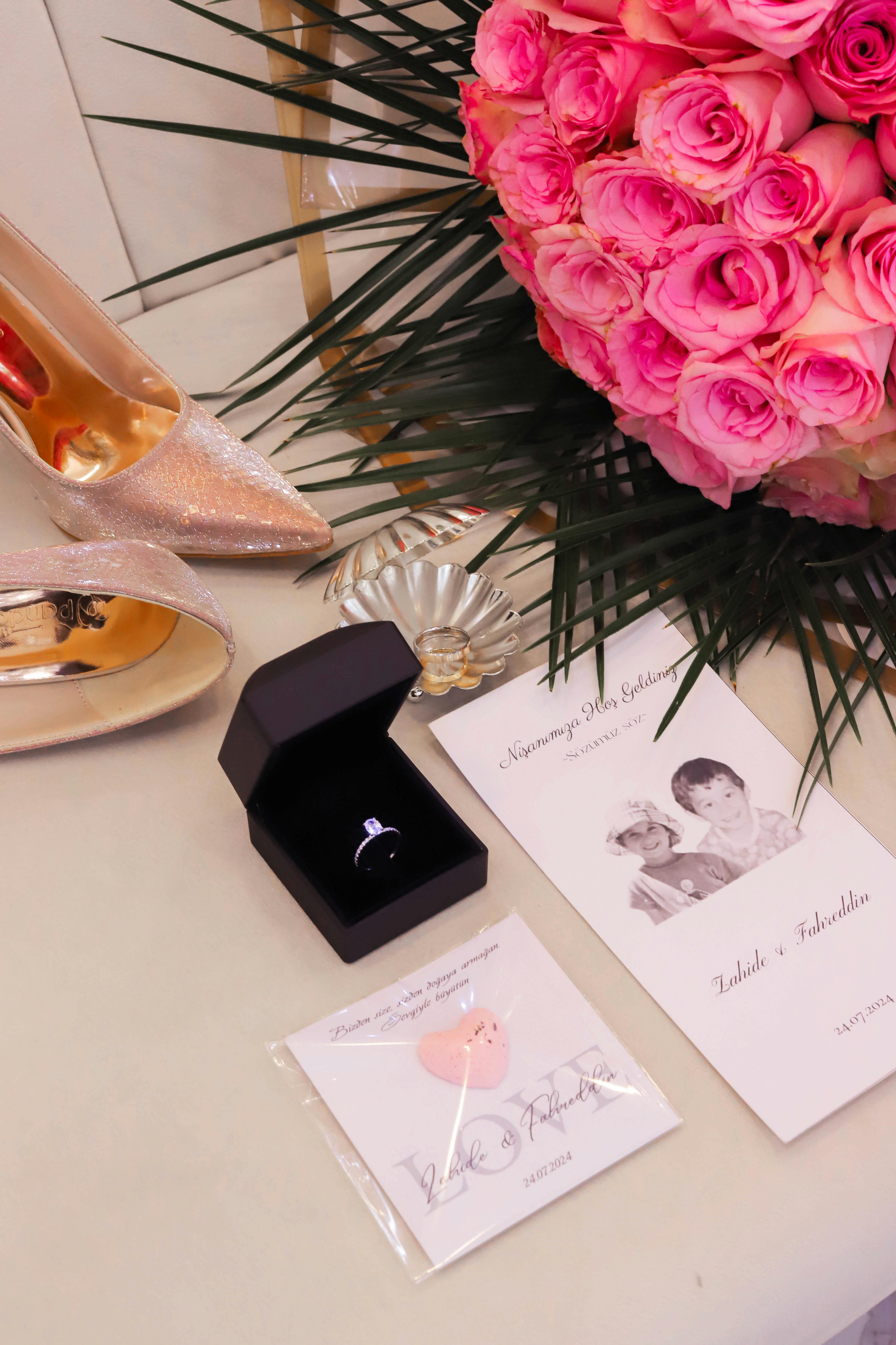 Luxurious wedding setup featuring pink roses, sparkling shoes, and a diamond ring for an elegant celebration.