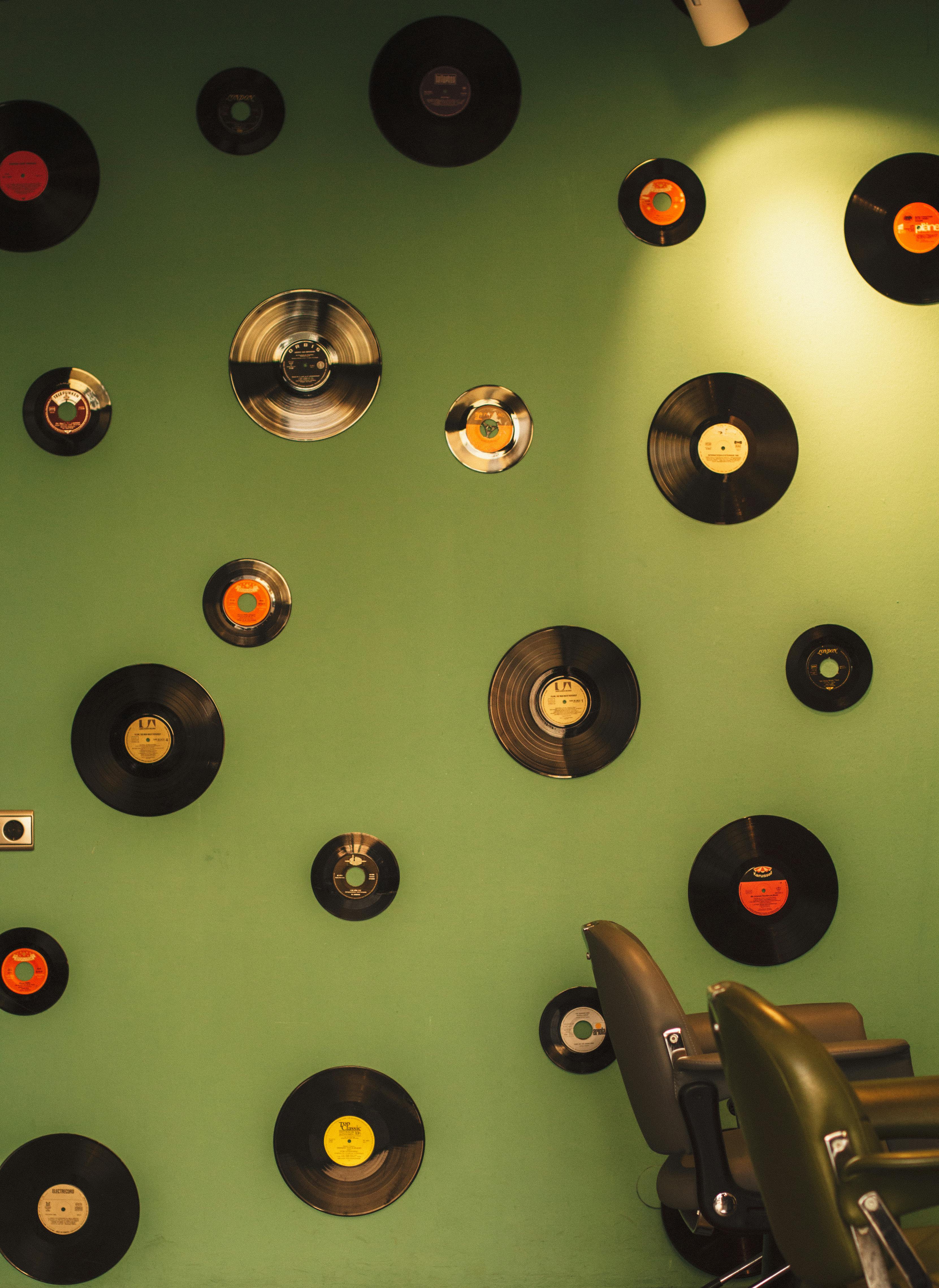 Aesthetic display of vintage vinyl records on a green wall in a retro-styled room.