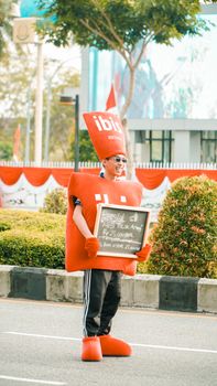 Person wearing a red costume holding a sign promoting a restaurant offer on a street. - Fotografer Sidoarjo