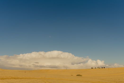 Expansive desert with distant vehicles under a vibrant sky in Faiyum, Egypt.