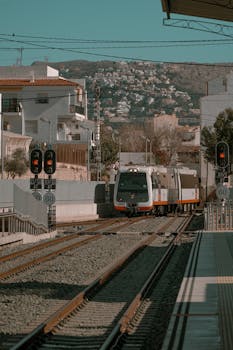 A modern train traveling through scenic Altea, Valencia, showcasing urban and natural landscapes.