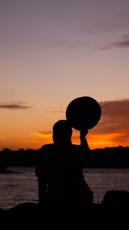 A figure silhouetted against low sun over the ocean — photo by Yunus Kilic on Pexels