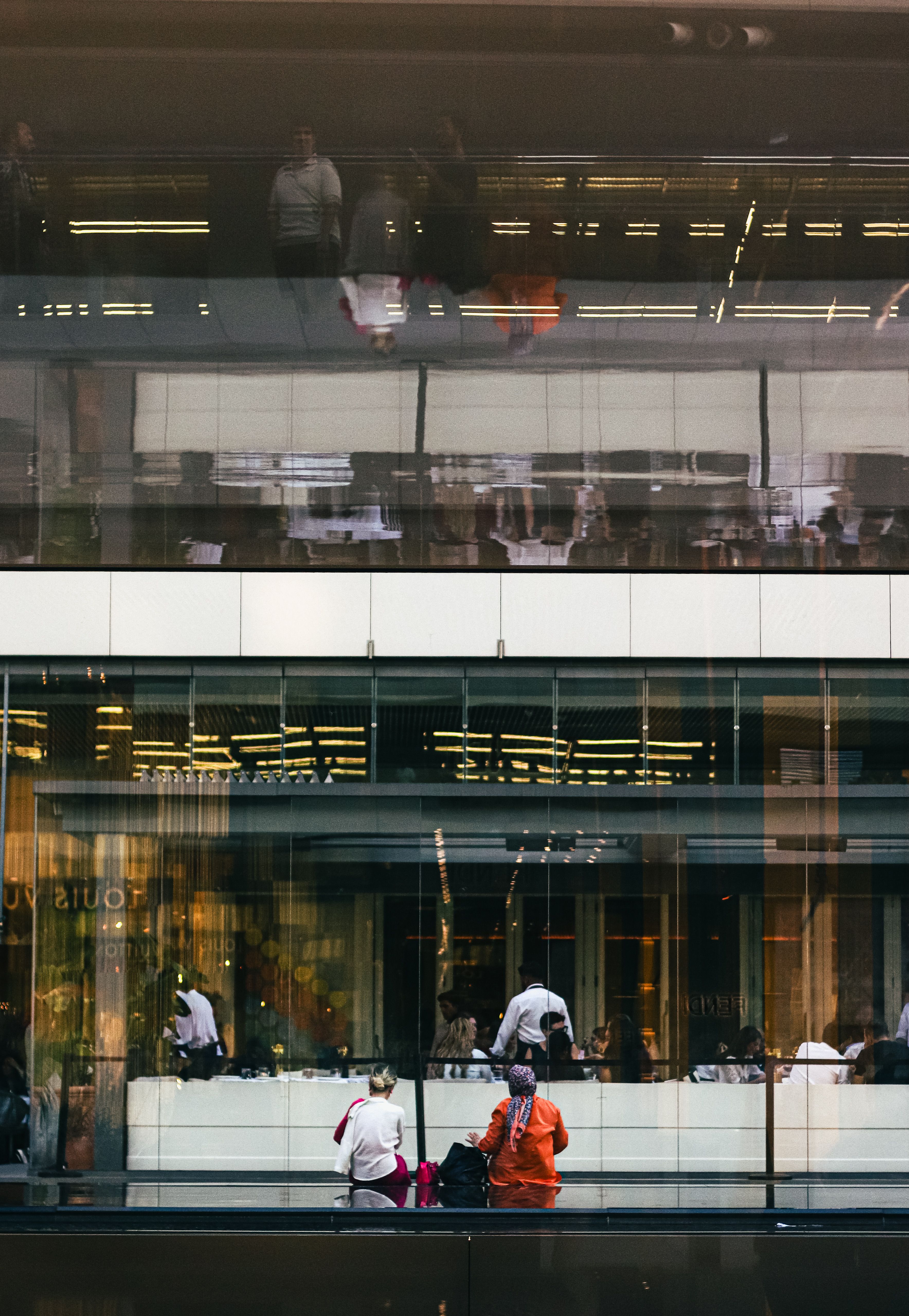 People are sitting in front of a glass building · Free Stock Photo
