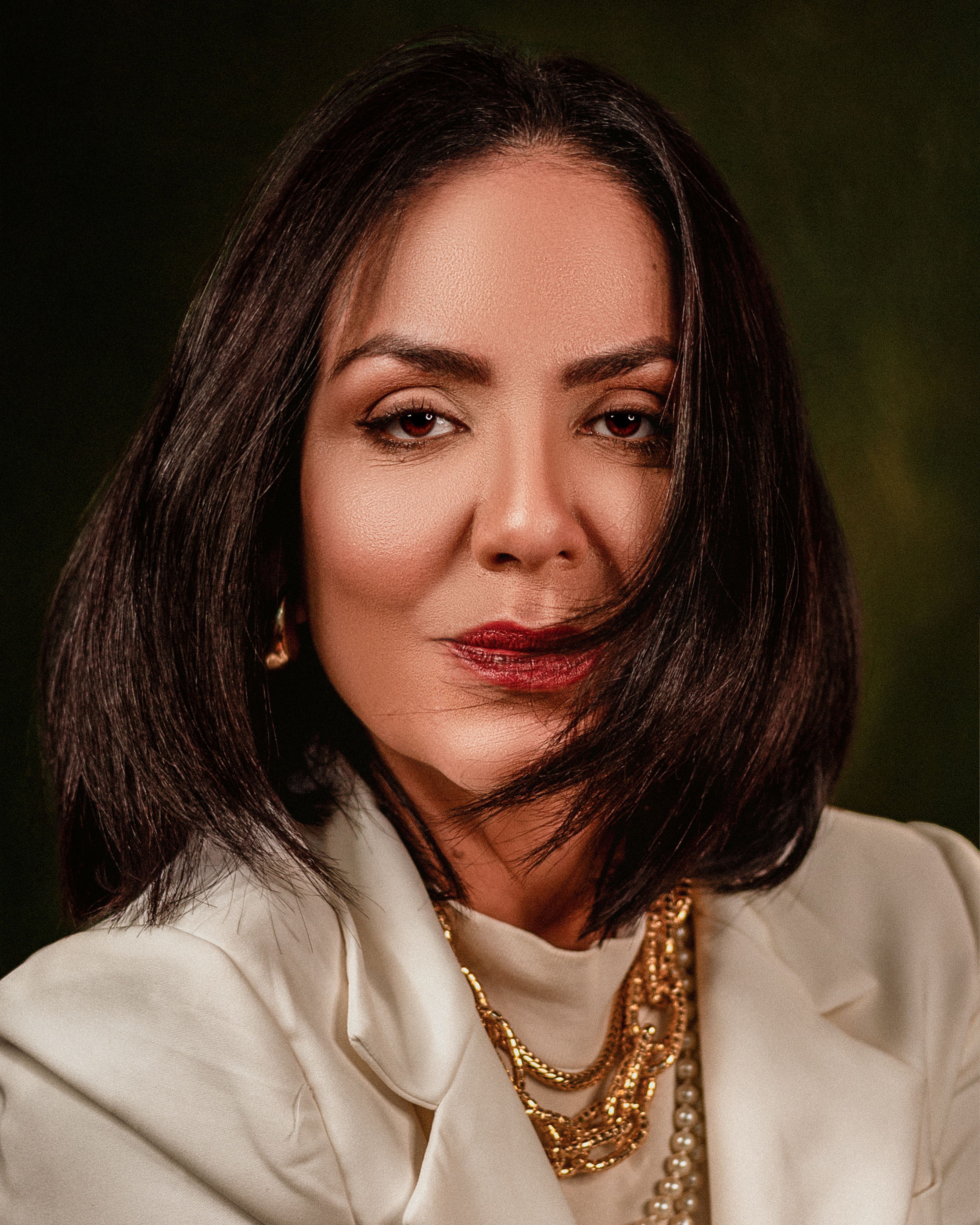 Sophisticated woman posing in studio with elegant jewelry.