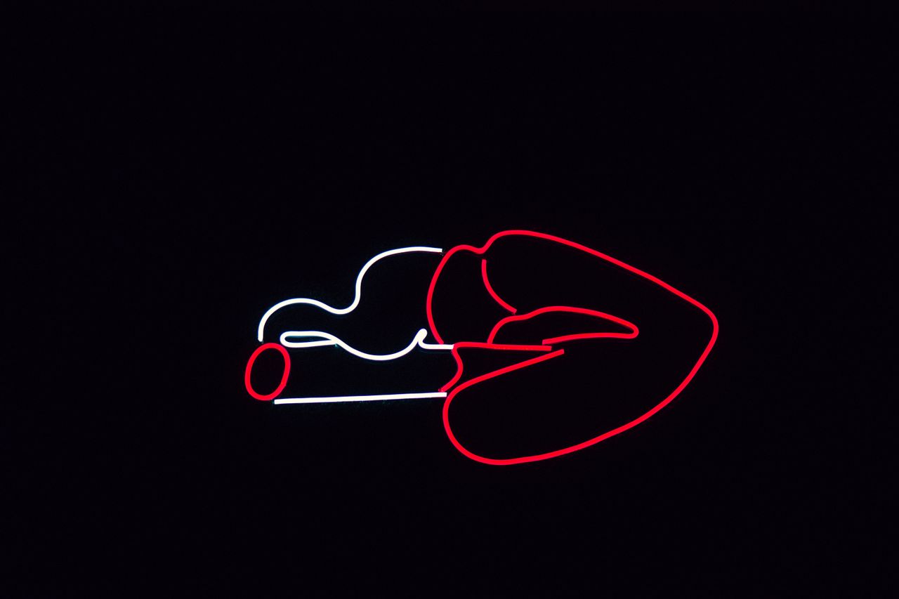 striking neon sign of lips with a cigarette glowing against a dark bac