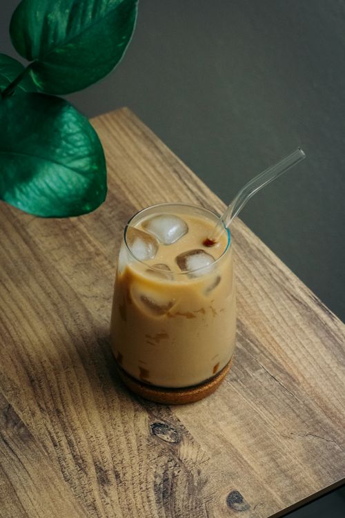 Free Iced coffee served in a glass with ice cubes on a wooden table, perfect for a cool beverage. Stock Photo
