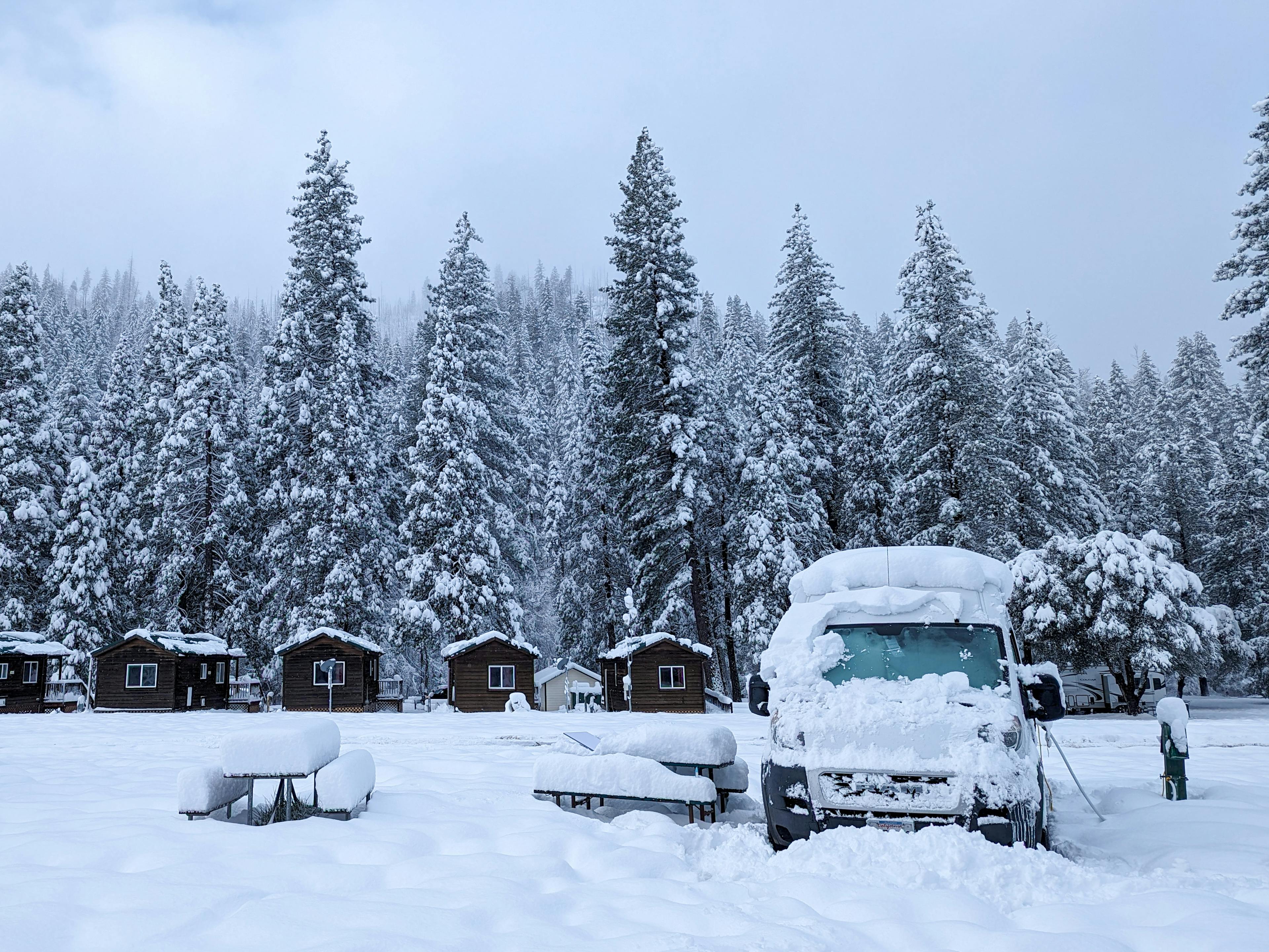 a van parked in the snow near a cabin