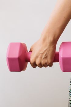 Close-up of person holding a pink dumbbell, signifying strength and fitness health.