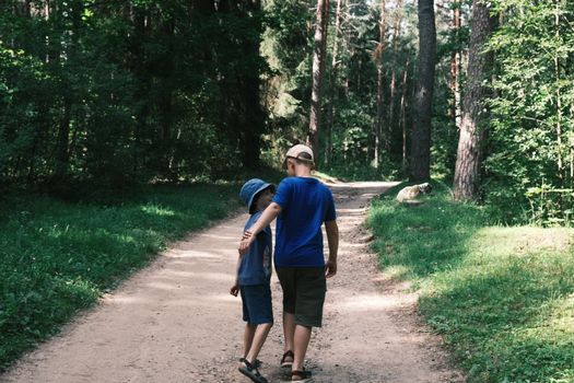 Two boys walking together on a forest path, enjoying a summer day outdoors.