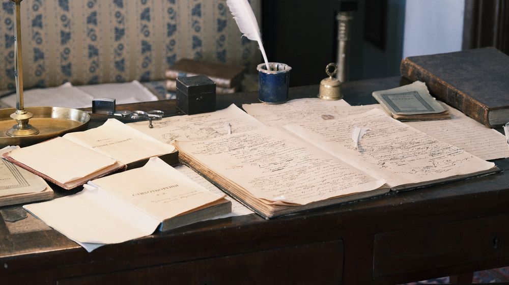 Cozy study with vintage desk, open books, and quill for a classic literary feel.