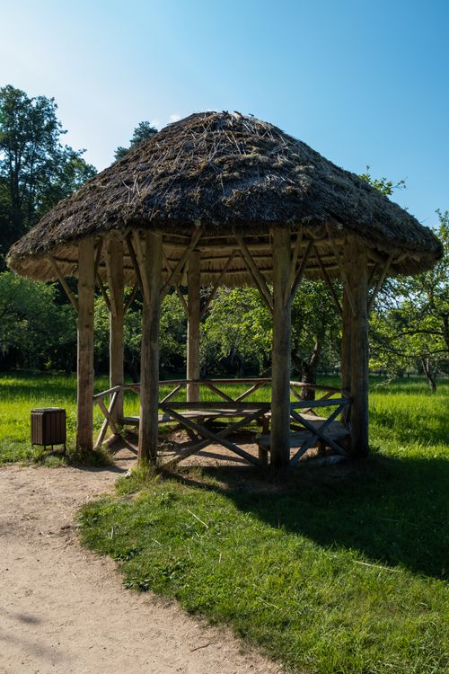 Free A charming wooden hut with a thatched roof situated in a bright, lush green park. Stock Photo