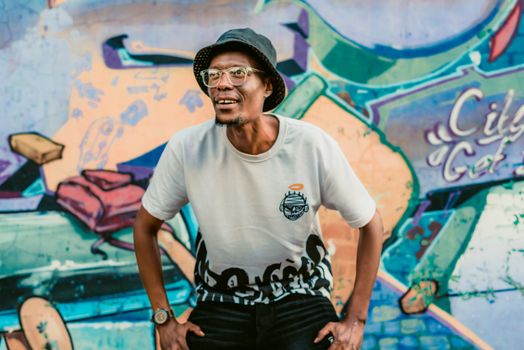 Man posing joyfully in front of a vibrant graffiti wall in Pretoria, South Africa.