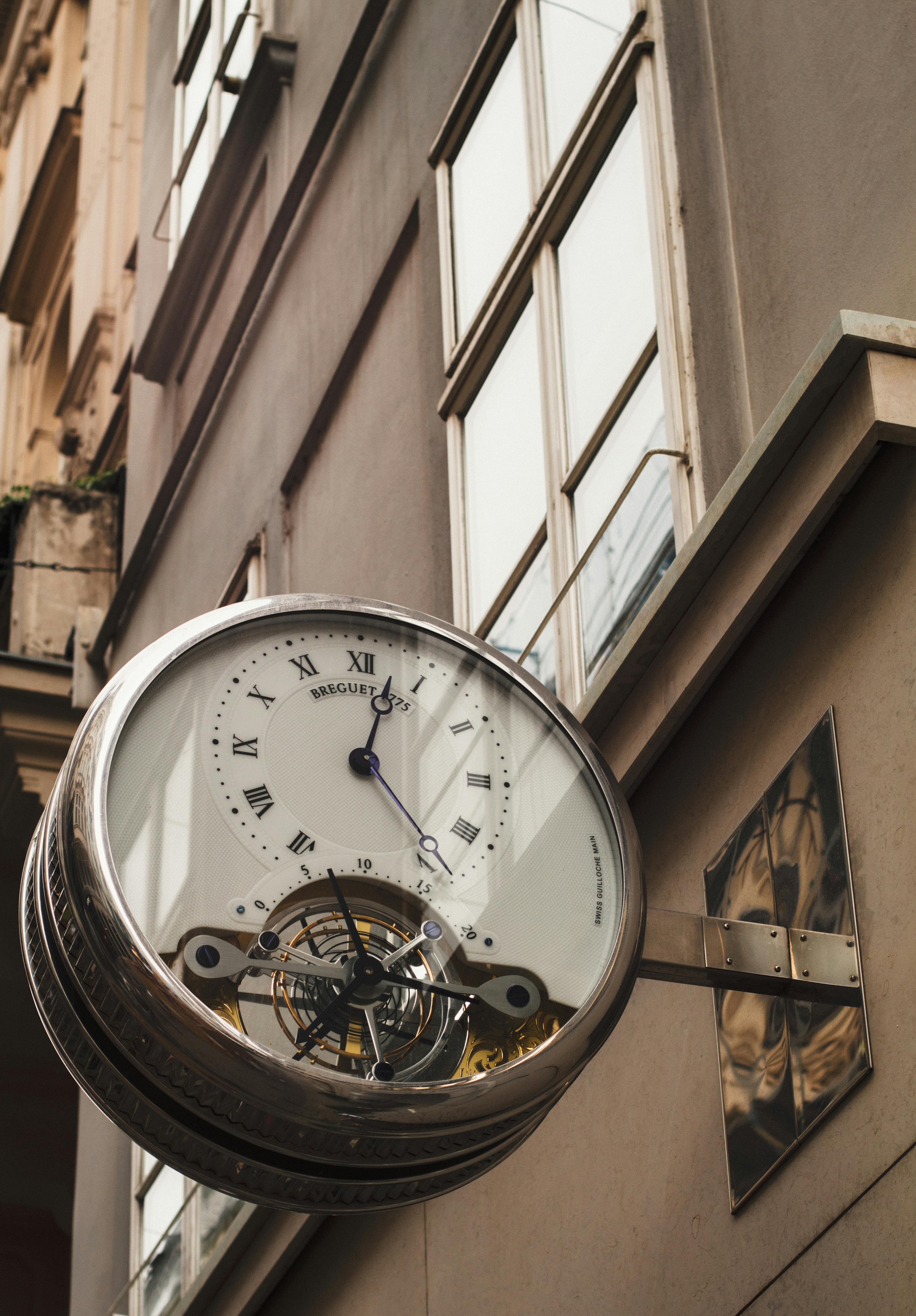 A contemporary urban wall clock with exposed gears on a city building.