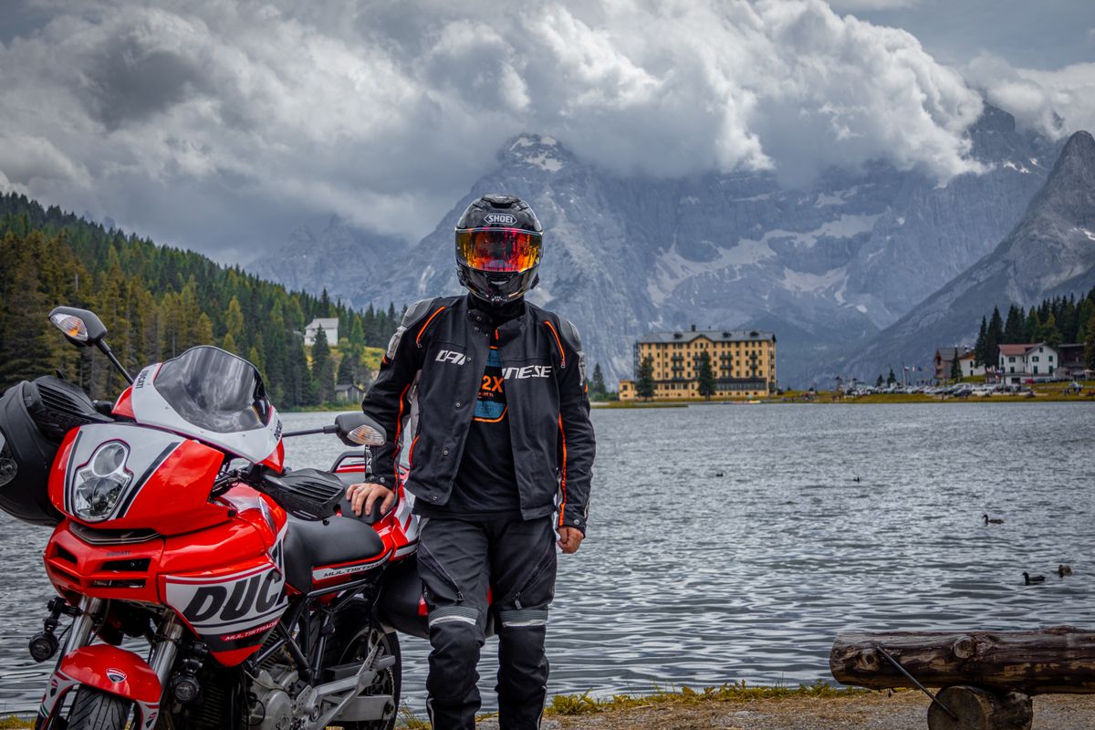 Motociclist in echipament complet langa un lac alpin