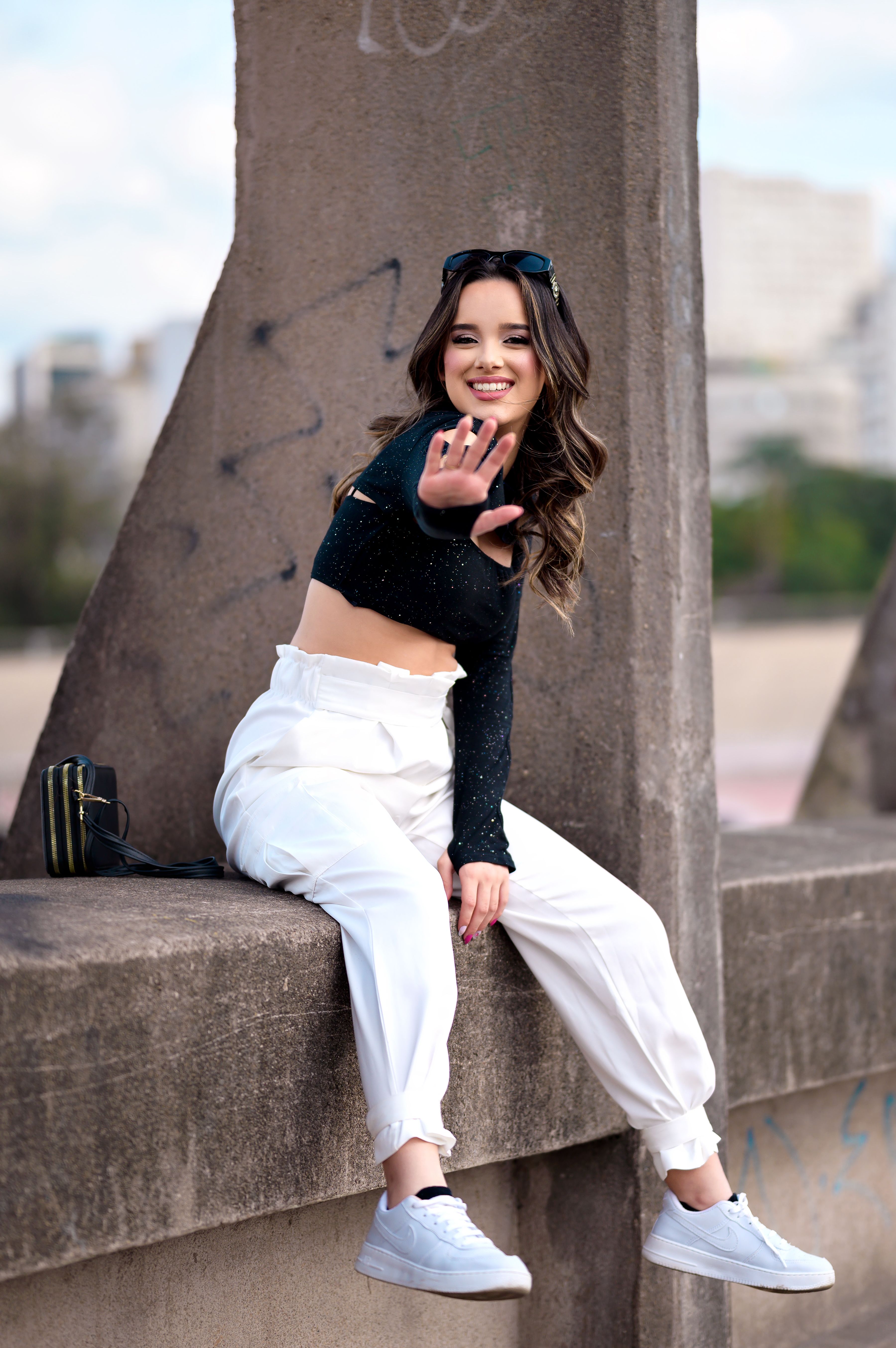 A woman in white pants and crop top sitting on a ledge · Free Stock Photo